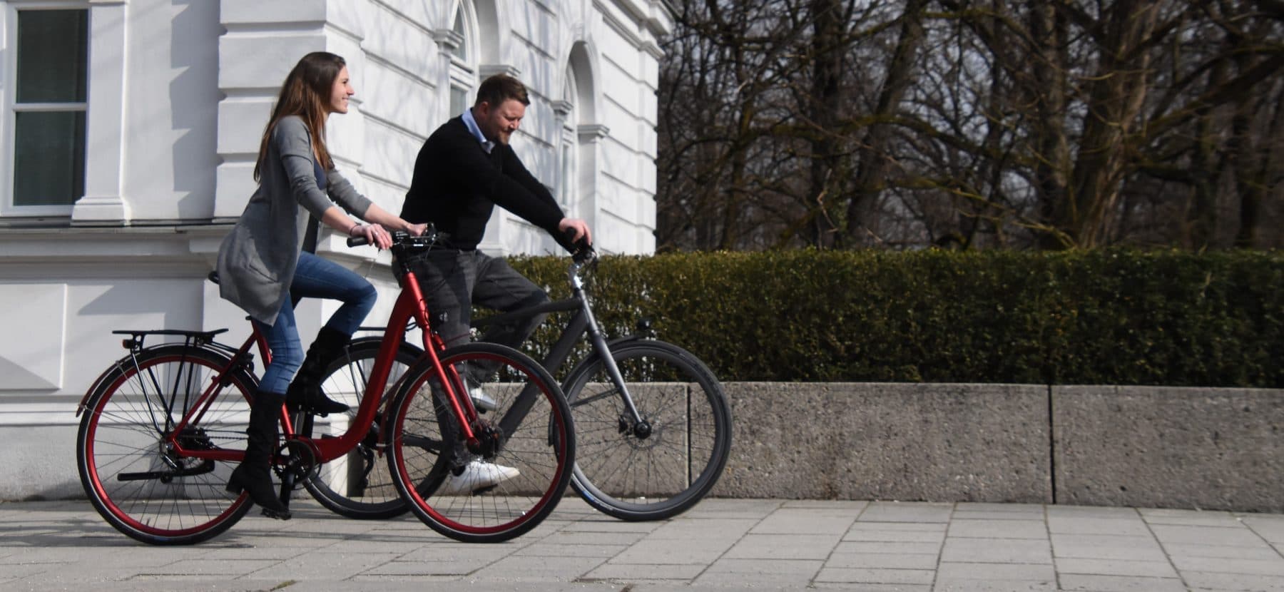 Zwei Menschen auf Leihrädern vor einem Münchner Altbau
